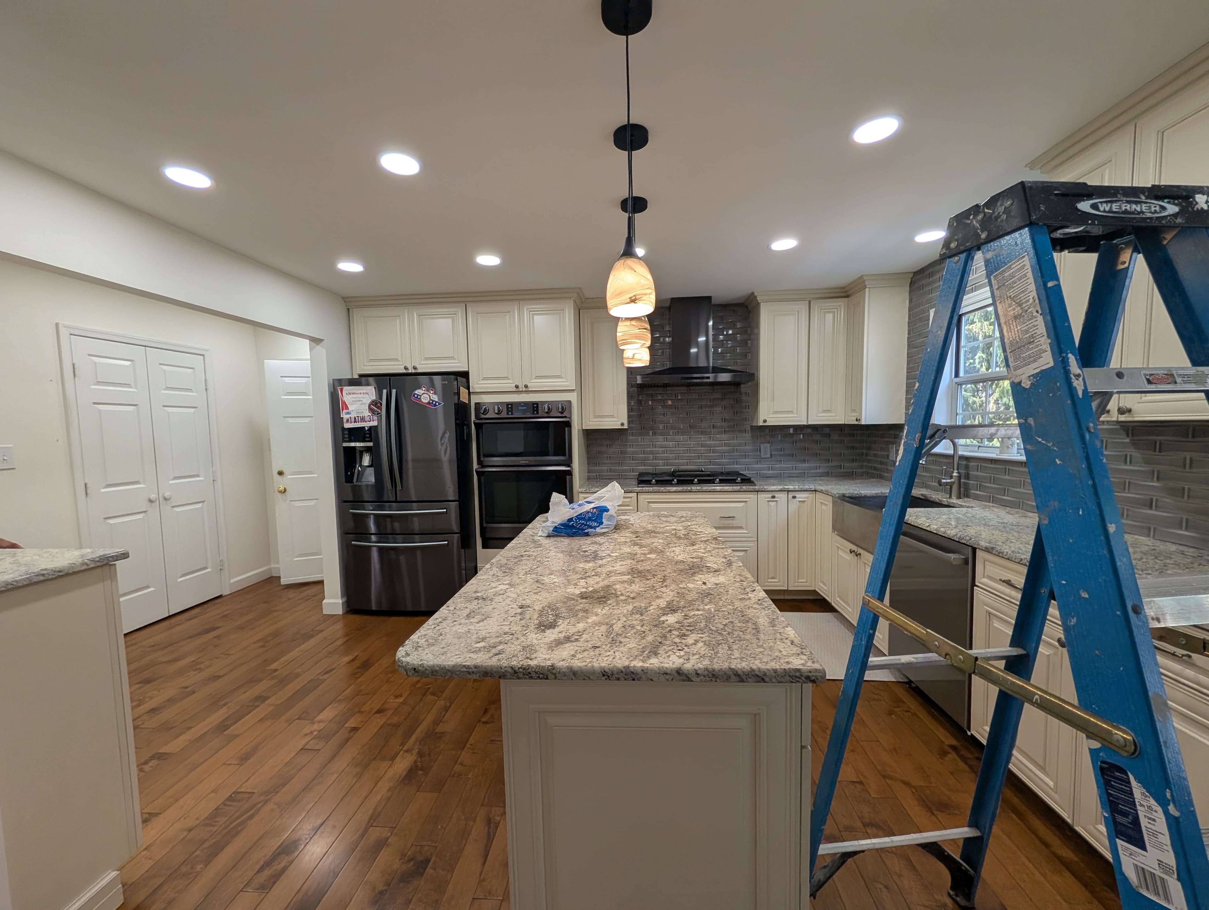 Original Herndon kitchen, wide view with black stainless appliances and pendant lighting
