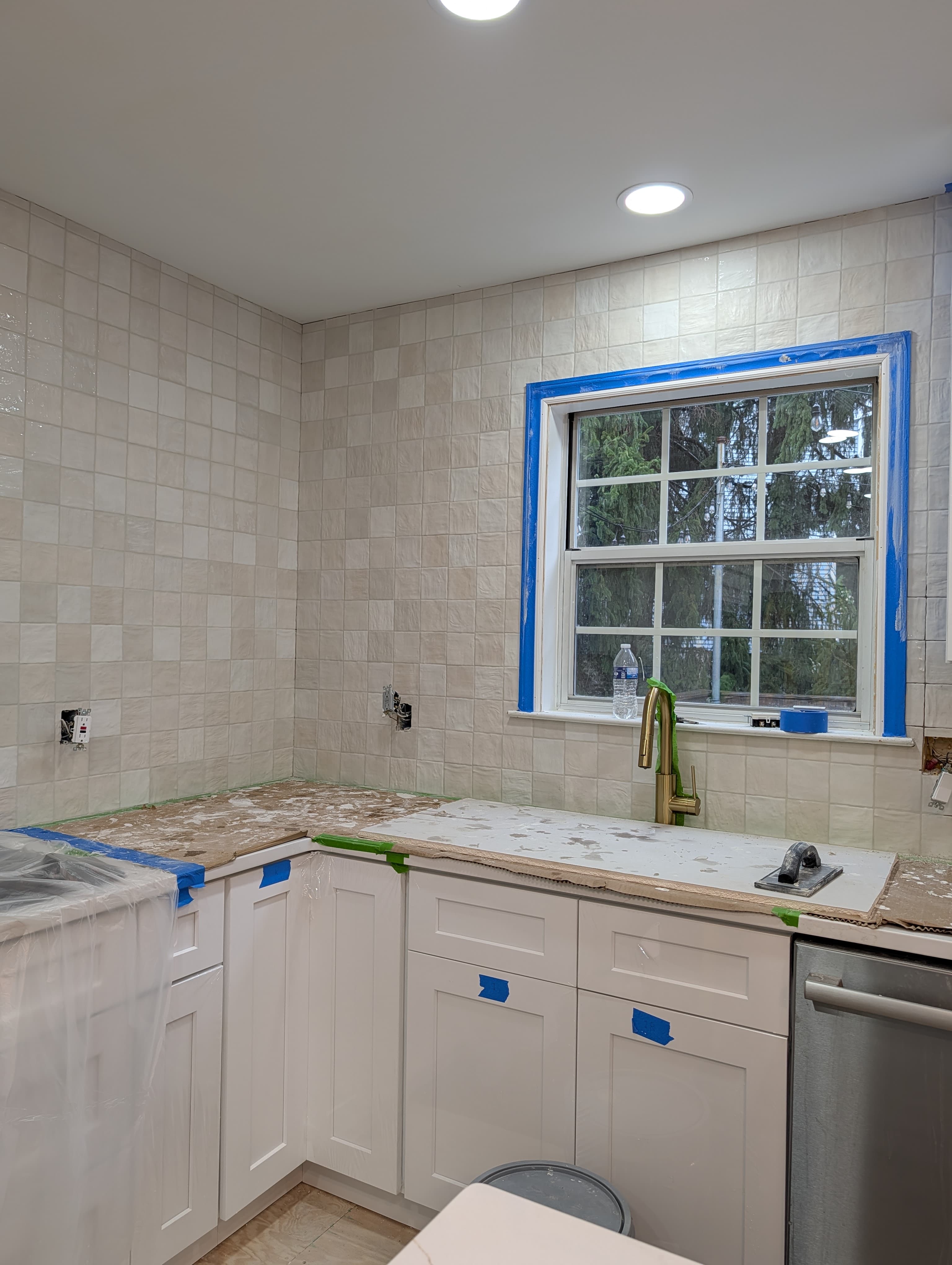 New Herndon kitchen in progress, white shaker cabinets with a square tile backsplash installed, countertops still protected